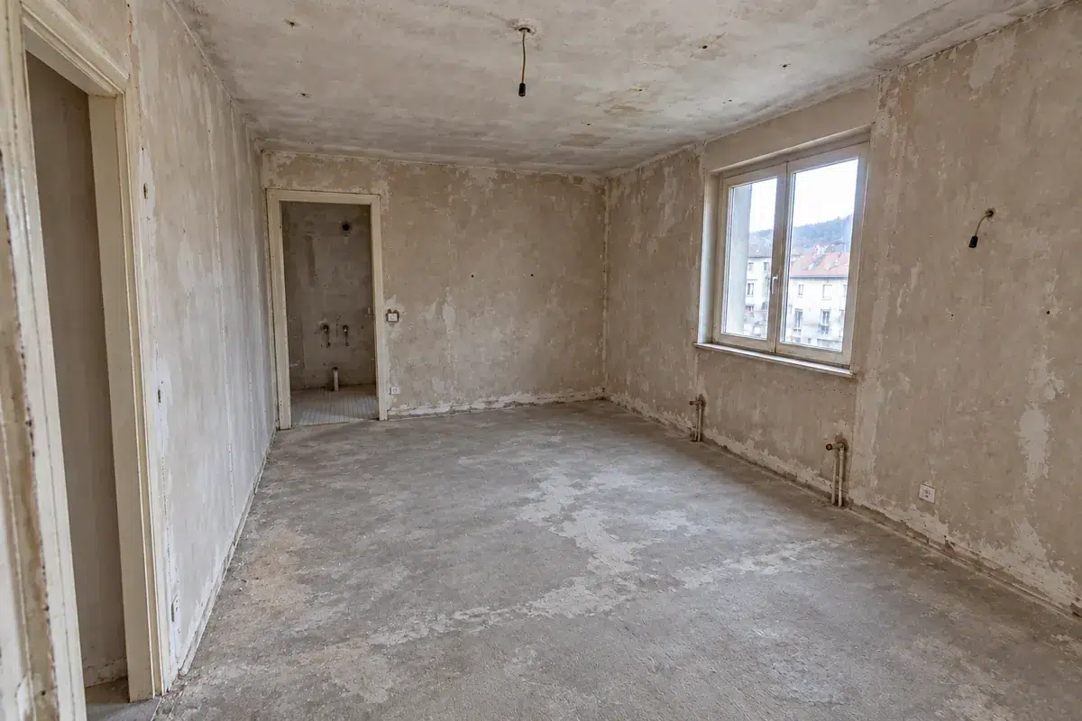 Même pièce après curage, murs et sol mis à nu, prête pour la rénovation